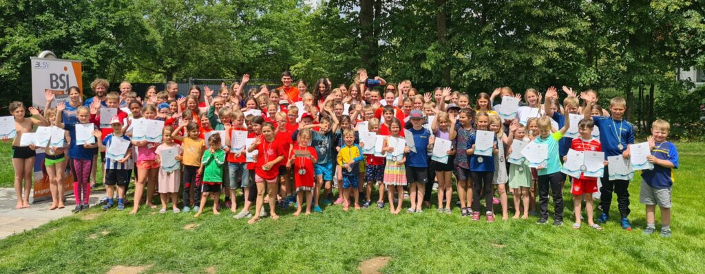 Sportbegeisterte Kinder in verschiedenen Trikots stehen in einer Gruppe zusammen und halten Urkunden in der Hand