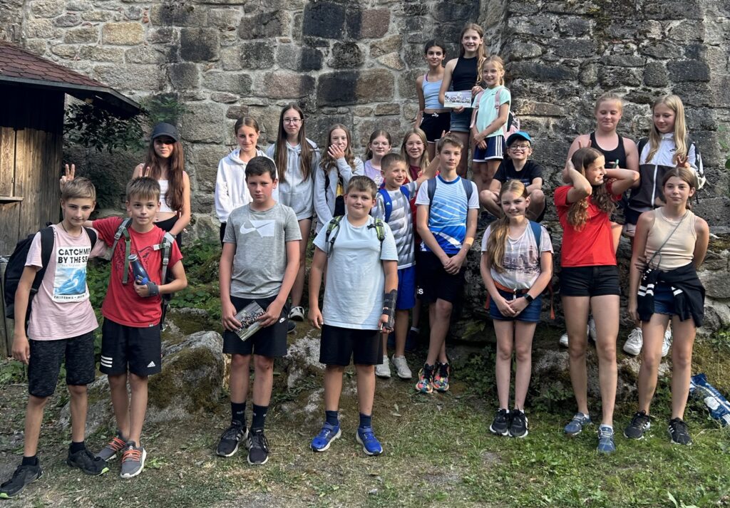 Eine Gruppe von Jugendlichen steht an einer alten Burgmauer für ein Foto zusammen