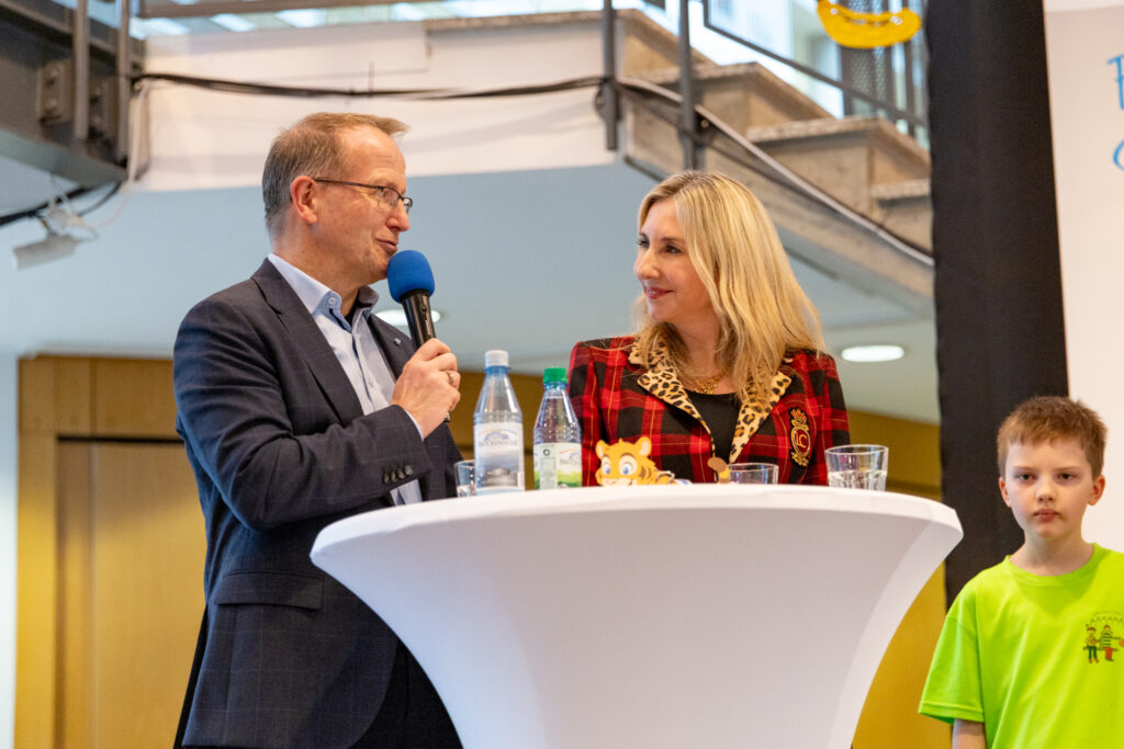 BLSV Präsident Jörg Ammon und Kultusministerin Anna Stolz stehen an einem Stehtisch und sehen sich an. Jörg Ammon sagt etwas in ein Mikrofon.